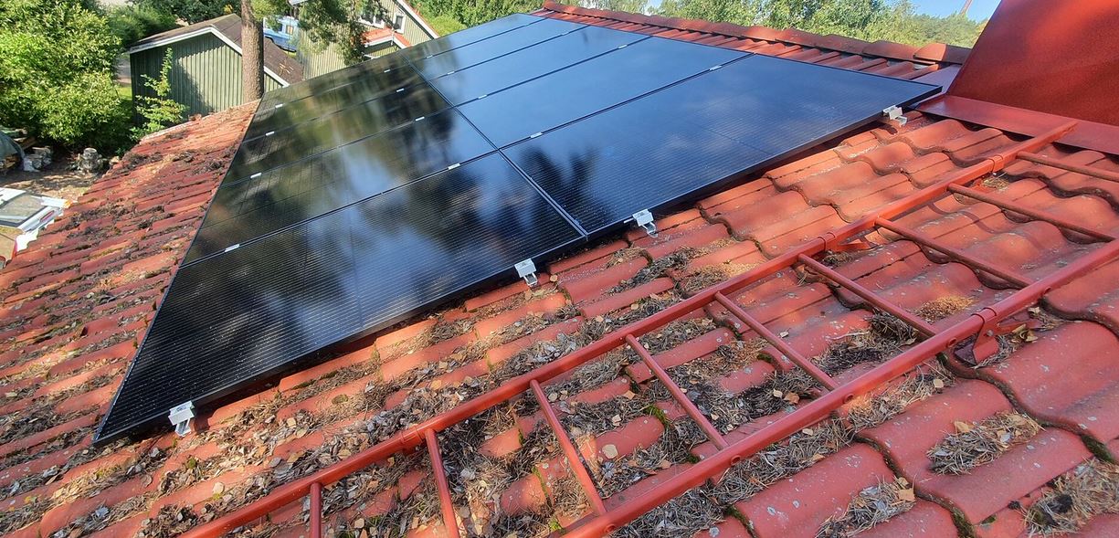 Solar panels on a tile roof. The adjacent roof surface looks like it may need maintenance.